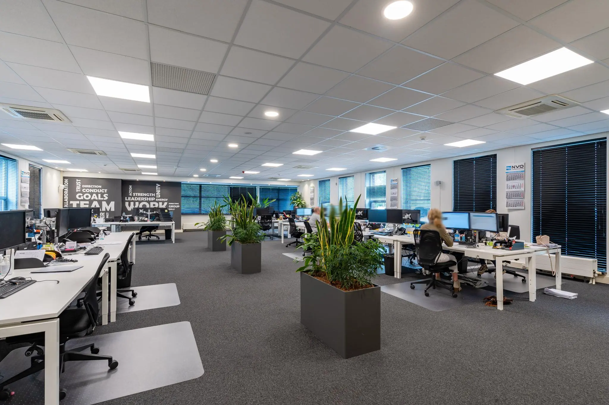 Modern kantoorinterieur aan de 1e Barendrechtseweg met open werkplekken, plantenbakken en bureaus met computerschermen.